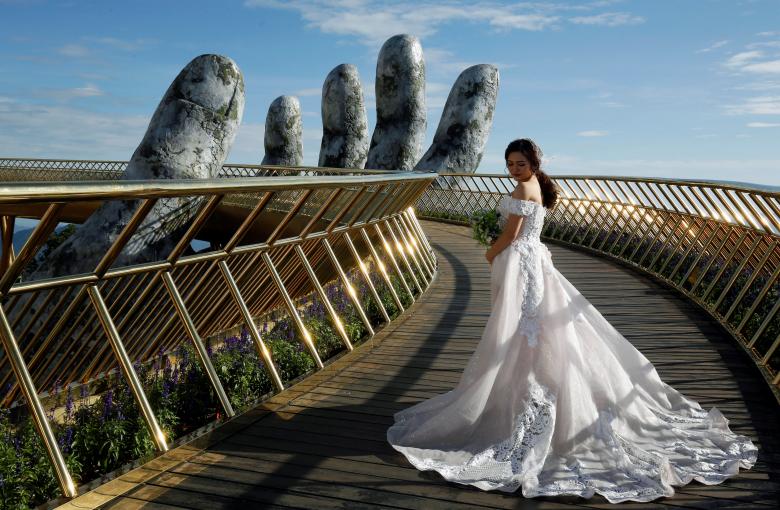 A Vietnamese bride poses for her wedding photos on Gold Bridge on Ba Na hill near Danang city