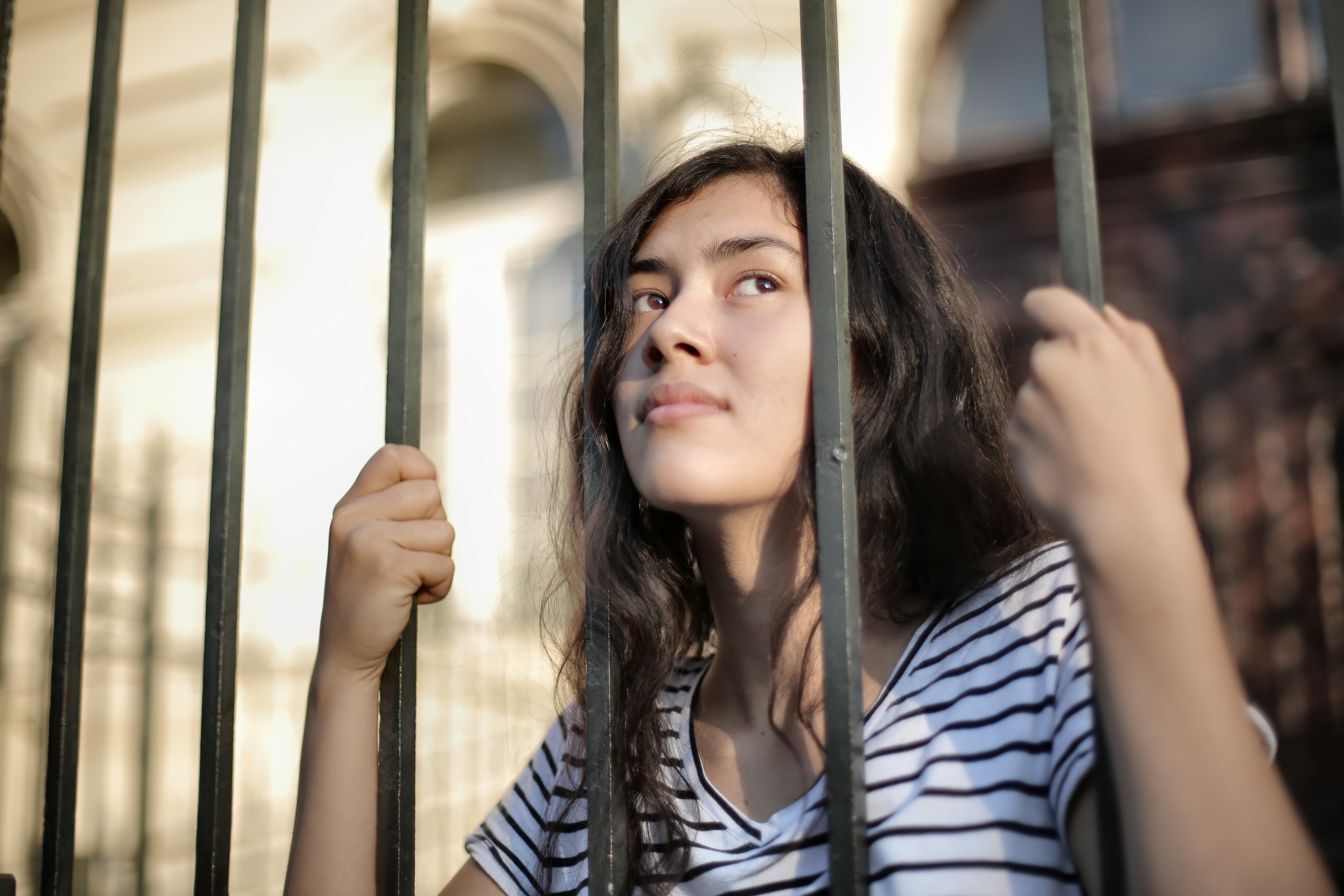 sad-isolated-young-woman-looking-away-through-fence-with-3808803